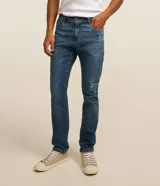 Pantalón skinny de jean nevado para hombre, confeccionado en denim de algodón con elastano. Presenta un lavado azul medio con ligeros desgastes y calce ajustado.