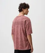 Remera masculina oversized de algodón con acabado desteñido y lavado desgastado de estilo vintage. Presenta cuello redondo de canalé y un pequeño bordado en el pecho con relieve.