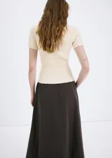 Chaleco de punto fino color amarillo claro, con diseño entallado, cuello polo y manga corta.