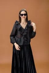 Camisa negra de manga larga con volados frontales y cuello en V. Presenta puños elásticos y una caída fluida.