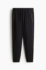 Jogging deportivo de color negro confeccionado con tejido funcional DryMove que ayuda a absorber la humedad. Cuenta con cintura elástica con cordón de ajuste, bolsillos laterales con cierre y puños elásticos en los tobillos.