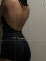 Catsuit negro con cuello alto, espalda descubierta y short ajustado. Incluye cinturón de cadena plateada con estrellas.