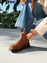 Botas cortas de cuero color marrón con elástico en los laterales y detalle de cuero texturizado en la parte delantera.