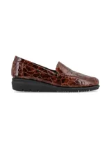Zapato tipo mocasín slip-on con acabado en cuero charol texturizado con efecto reptil en tonos marrones. Presenta una suela de plataforma plana de color negro con diseño dentado y una estructura anatómica para mayor confort.
