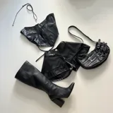 Top negro de cuero sintético con textura de cocodrilo, cierre frontal con cremallera y tirantes finos.