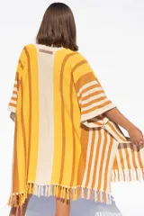 Ruana tejida a rayas horizontales en tonos amarillo, naranja y blanco, con flecos en el borde inferior.