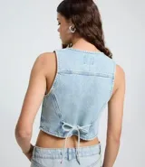 Chaleco de jean con escote en V, cierre frontal con botones metálicos y ruedo redondeado. Presenta un diseño clásico con lazo ajustable en la espalda.