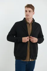 Cardigan de tejido de punto color verde militar, con cierre frontal de metal y cuello redondo. Presenta detalle de tejido plano en la cartera del cierre y en los bolsillos laterales.