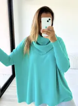 Polerón de punto color verde agua, con diseño mega oversize y cuello caído tipo polera. Presenta mangas largas con puños acanalados.