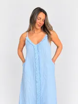 Vestido maxi de lino color blanco, con escote en V, tirantes finos regulables y detalles de flecos en el frente.