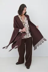 Ruana de tejido de punto en color negro, con diseño de cuello alto y terminaciones con flecos en los bordes.