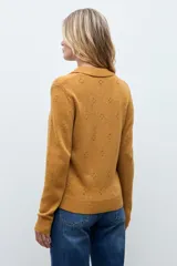 Cardigan de punto color ocre, con diseño calado de pequeños motivos florales, cuello polo y cierre frontal con botones.