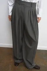 Pantalón de tiro medio con pinzas frontales, confeccionado en tejido con viscosa. Presenta cintura con trabillas, bolsillos laterales y cierre frontal con cremallera, botón y ganchos metálicos.
