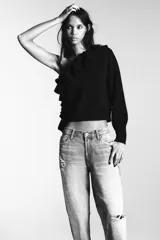 Jersey de punto con diseño asimétrico de un solo hombro, decorado con volantes en el escote y lateral. Presenta manga larga y corte ajustado con puños y ruedo acanalados.