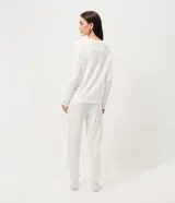 Pijama de dos piezas confeccionado en tejido de punto acanalado color blanco con estampado de pequeñas cerezas. Incluye una blusa de cuello redondo y manga larga, y un pantalón con cintura elástica y puños ajustados en los tobillos.