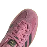 Championes adidas Gazelle Indoor de gamuza en color rosado con las icónicas tres tiras laterales en negro. Presenta un diseño clásico de perfil bajo con suela de goma translúcida y detalle en el talón en color azul oscuro.