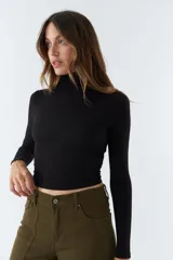 Polera negra de cuello alto y manga larga, de corte ajustado.