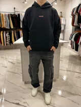 Canguro oversize negro con capucha y bolsillo tipo canguro. En la espalda presenta una estampa grande con diseño de mariposa, texto y la inscripción "top style" en color coral.