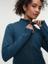 Campera deportiva marrón con cuello alto y cierre frontal completo. Presenta mangas largas con orificio para el pulgar y corte ajustado.