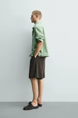 Camisa de corte relajado confeccionada en tejido fluido con mezcla de lyocell. Presenta diseño de rayas verticales, cuello solapa, manga larga con puños abotonados, bolsillos de plastrón con solapa en el pecho y cierre frontal con botones a presión.