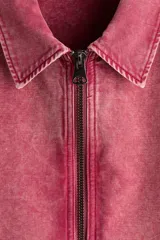 Campera de algodón color rosa con efecto acid wash, cierre frontal, cuello camisero, bolsillos delanteros ribeteados y puños con botón.