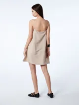 Vestido corto color beige, de breteles finos y escote recto. Cuenta con lazos laterales al costado del busto.