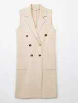 Chaleco largo tejido color blanco de la marca Sioni, con cuello solapa, doble botonadura dorada en el frente y bolsillos aplicados.