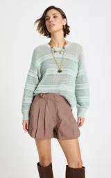 Sweater de punto calado color verde menta, con cuello redondo y diseño de rayas horizontales texturizadas, de mangas largas y corte holgado.