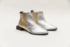 Botín corto de cuero negro con detalle de cuero dorado en el talón y textura de cocodrilo en el lateral. Tiene cierre lateral y taco cuadrado.