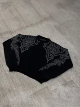 Sweater negro con cuello redondo y diseño geométrico en gris en la parte superior del pecho y hombros.