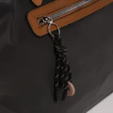 Cartera tipo tote bag color negro, con asas de cuero color marrón y cierre superior con cremallera.
