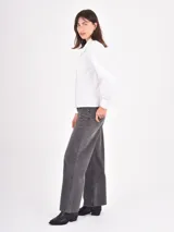 Camisa blanca de manga larga con cuello estilo bebé con volados y puños abotonados. Presenta un cierre frontal con botones a tono.