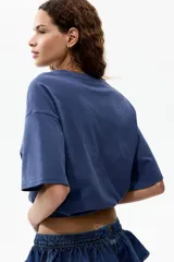 Remera oversized de algodón color azul, con hombros caídos, cuello redondo y estampa gráfica frontal de estilo artístico en tono claro.
