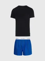 Conjunto de pijama Calvin Klein compuesto por una remera negra de algodón con cuello redondo y mangas cortas, y un short azul estampado con cintura elástica con el logo de la marca.