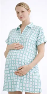 Camisa maternal de corte holgado y largo midi, confeccionada en viscosa suave con estampado geométrico de cuadros en color verde agua y blanco. Presenta cuello camisero, mangas cortas y bolsillos laterales.