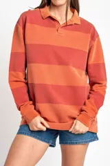 Sweater tipo polo de algodón peinado con diseño de rayas horizontales en tonos rojizos y terracota, cuello camisero y mangas largas con puños.