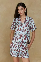 Camisa manga corta con estampado abstracto en tonos celeste, marrón y blanco. Tiene cuello tipo solapa y cierre frontal con botones.