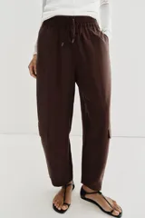 Pantalón de tiro medio con cintura elástica ajustable con cordón. Presenta un diseño de paneles laterales en tejido técnico contrastante y bolsillos tipo cargo. Su corte es holgado con pernera que se estrecha hacia el tobillo.