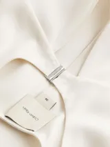 Blusa blanca de satén con cuello redondo con abertura en forma de V y mangas cortas.