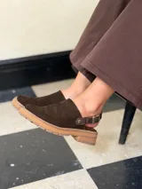 Zueco de cuero color chocolate con diseño cerrado en la parte frontal y suela de goma con plataforma baja.