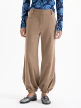 Pantalón color tostado confeccionado en lanita, con fit amplio y cómodo. Tiene bolsillos ocultos en el delantero y bolsillos ojal en la parte trasera. Presenta presillas y ajuste en los tobillos mediante elástico, que aporta una silueta relajada y caída.