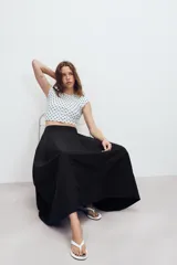 Falda midi de tiro alto en color verde militar, con diseño acampanado y cintura elástica. Presenta costuras verticales que definen su estructura y cierre lateral con cremallera oculta.