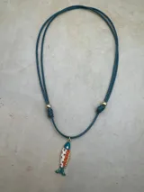 Collar con cordón ajustable de color y dije de pez esmaltado con detalles de piedras de colores.