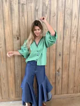 Camisa de rayas azules y blancas, de corte holgado con mangas abullonadas, escote en V y detalle de bordado rojo alrededor del cuello.