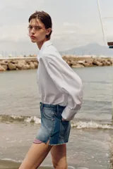 Shorts de jean tiro medio, corte mom fit, con bajo deshilachado y forro de bolsillos delanteros estampado a cuadros que asoma por debajo.