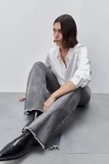 Jean flare de tiro alto, color azul, con calce ajustado en cadera y muslos, y ruedo desflecado.