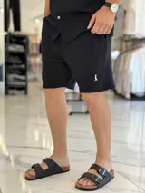 Bermuda blanca de tejido texturizado, con pequeño bordado oscuro en la parte inferior izquierda.