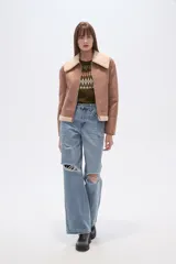 Campera estilo aviador color marrón claro, con cuello y forro de corderito color beige. Presenta cierre frontal y puños y ruedo con terminación de corderito.