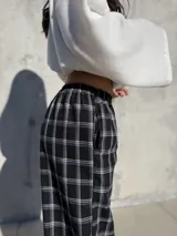 Pantalón de viyela con estampado de cuadrillé en blanco y negro. Presenta un diseño de silueta holgada con elástico en la cintura y en los puños, ofreciendo un estilo relajado y cómodo.