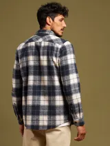 Camisa a cuadros azul marino y beige, de manga larga, con cuello clásico y dos bolsillos con solapa abotonada en el pecho.